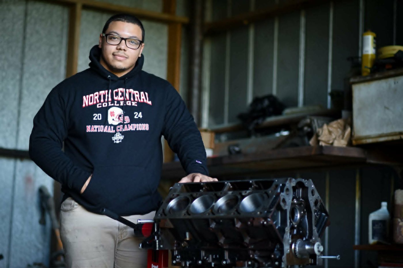 Jayden Lavespere, owner of Remote Auto Repair, beside a bare V8 engine block in his shop