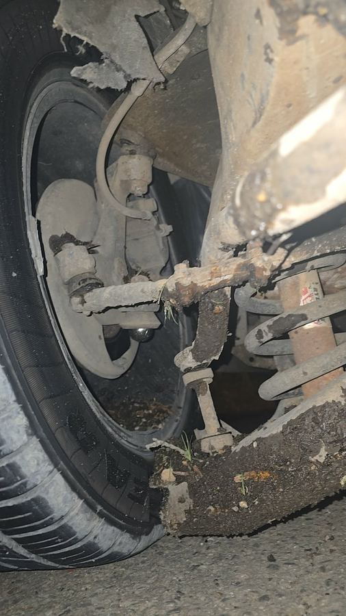 Heavily corroded control arm and tie rod on a worn front suspension